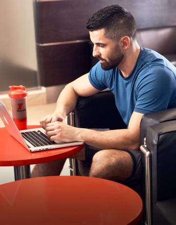Fitness first member using his laptop in the lounge Fitness first member using his laptop in the lounge