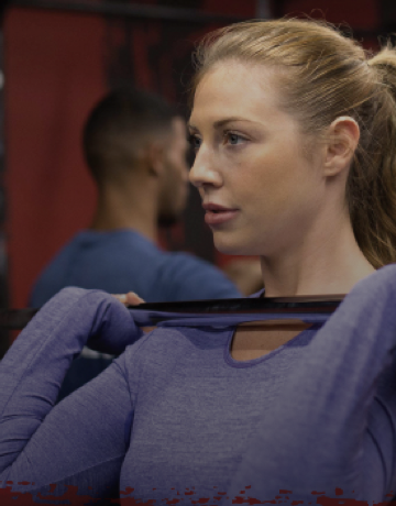 Female Fitness First member lifting weight barbell